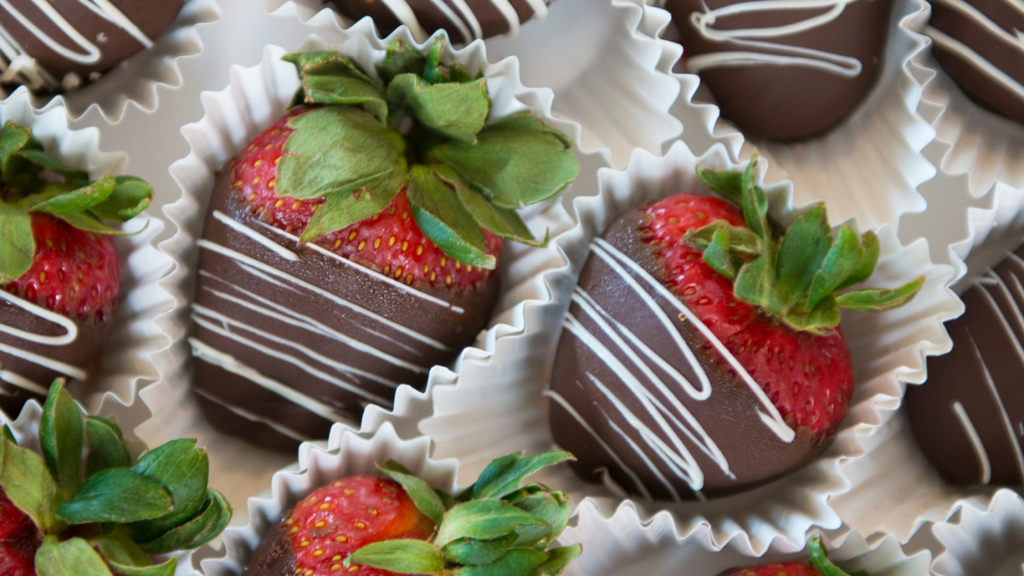 chocolate covered strawberries recipe with white chocolate drizzle on top in individual paper holders