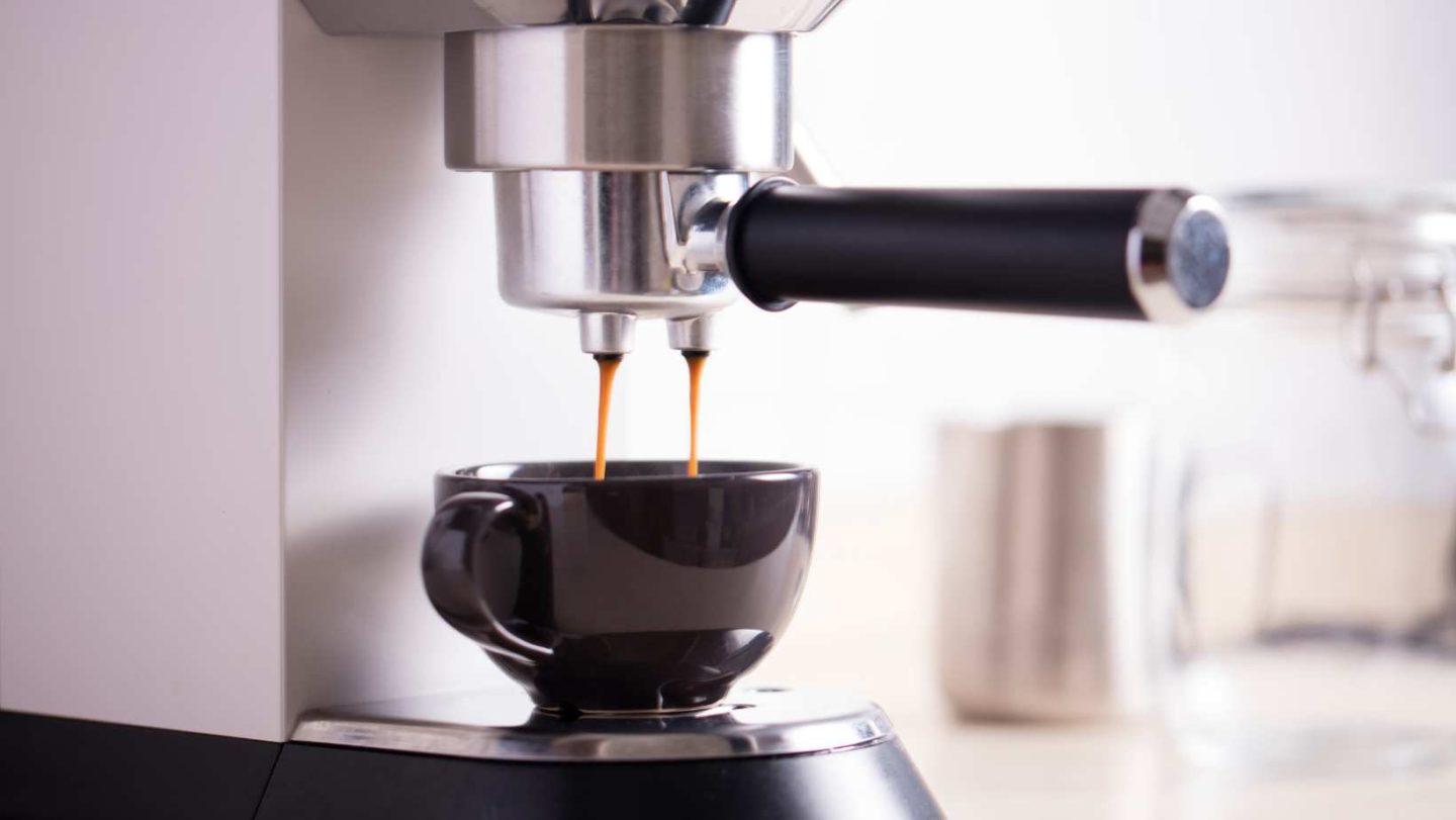 moka pot vs espresso - espresso machine dripping espresso into a black mug