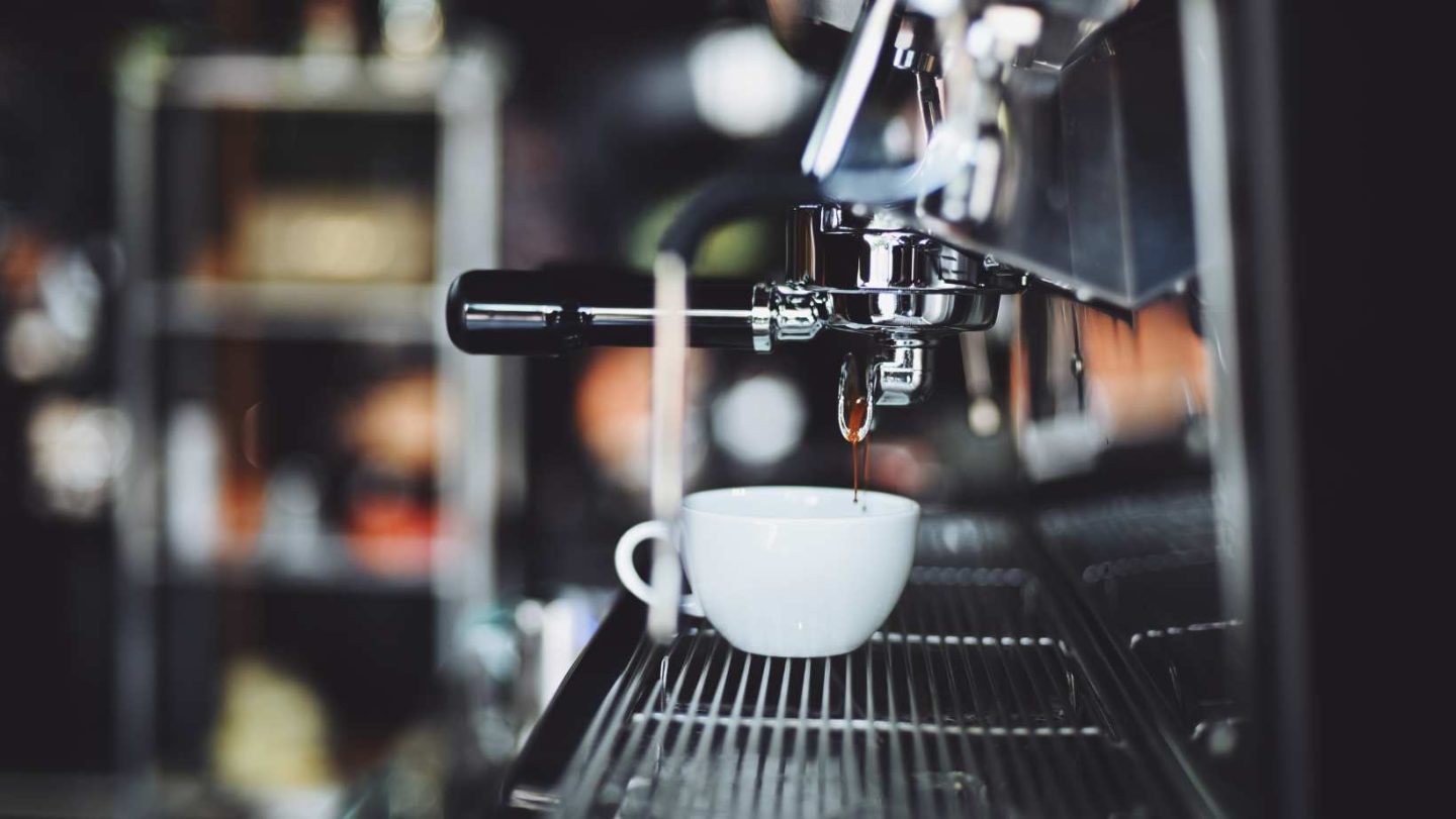 moka pot vs espresso - industrial size espresso machine dripping espresso into a white mug