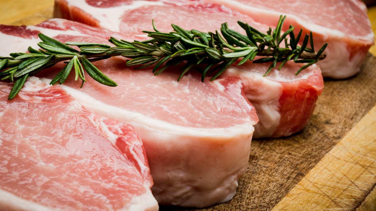 Pork Cutlet vs Pork Chop - raw pork chop on a wooden cutting board