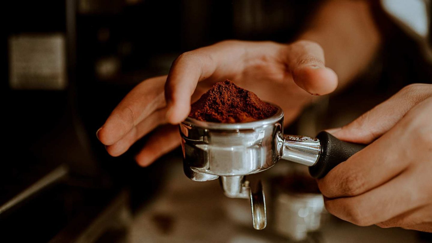 moka pot vs espresso - a person leveling off ground coffee beans in a portafilter in preparation for making espresso